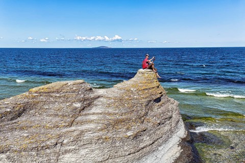 Hiker sitting on limestone pillar photographing landscape