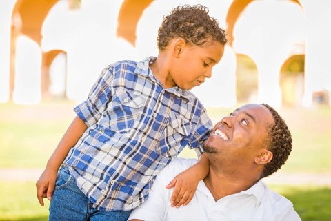 Happy african american father and mixed-race son playing at the park