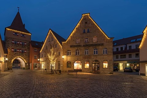Historic gabled houses and the Hersbruck Gate with Christmas lighting on the market square in the evening