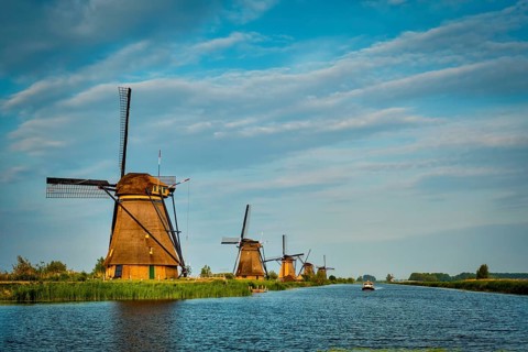 Netherlands rural lanscape with windmills at famous tourist site Kinderdijk in Holland on sunset with dramatic sky