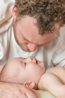 mixed-race chinese and caucasian baby boy laying in bed with his father