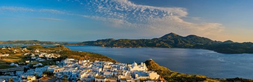 Panorama of Plaka village on Milos island with traditional greek white houses on sunset
