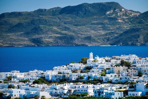View of Plaka village with traditional Greek church and white painted houses and ocean coast