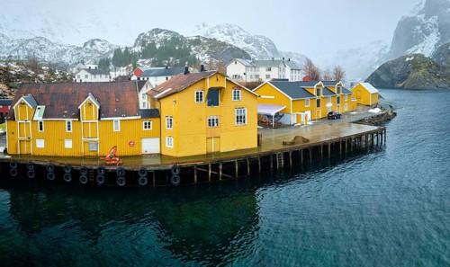 Panorama of Nusfjord authentic fishing village with yellow rorbu houses in Norwegian fjord in winter. Lofoten islands