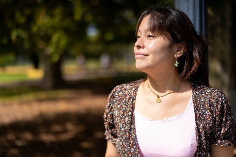 Portrait of a young Latin woman in a park leaning on a lamppost
