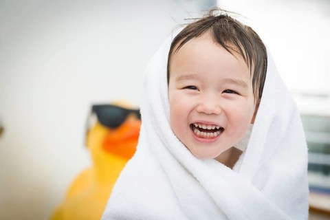 mixed-race boy having fun at the water park with large rubber duck in the background