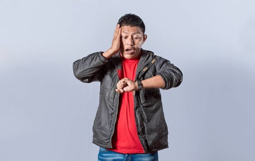 Young man in jacket looking at the watch time worried
