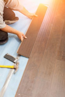 Man installing new laminate wood flooring abstract