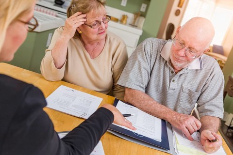 Senior adult couple going over documents in their home with agent at signing