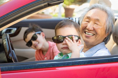 Chinese granfather and mixed-race children playing in parked car