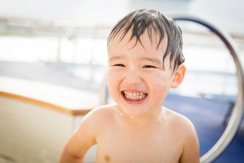 mixed-race boy having fun at the water park with large rubber duck in the background