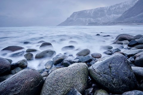 Waves of Norwegian sea surging on stone rocks at Unstad beach
