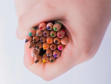 Hand holding color Pencils placed on a white background