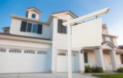 Blank real estate sign in front of beautiful new house
