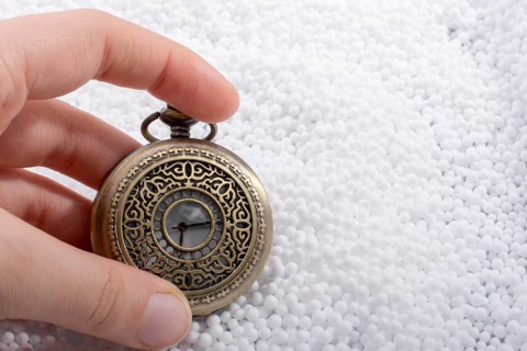 Retro style pocket watch in hand on white background