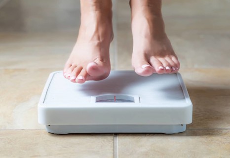 Woman floating slightly above surface of weight scale