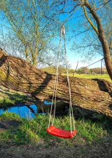 Red children's swing in the Tegeler Fliess in Luebars