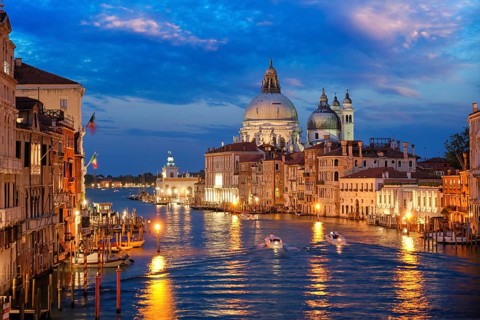 View of Venice Grand Canal with boats and Santa Maria della Salute church in the evening from Ponte dell'Accademia bridge. Venice