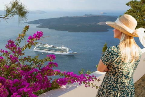 Attractive female tourist admiring the view of the cruise ship off the coast of santorini Greece