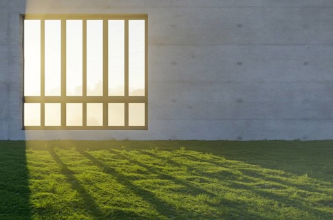 Window with bright sun light shining through concrete wall in grass and rocks field