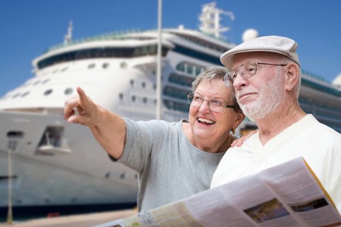 Happy senior adult couple tourists with brochure next to passenger cruise ship