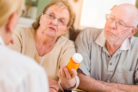 Doctor or nurse explaining prescription medicine to senior adult couple