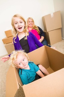 Playful young family in empty room playing with moving boxes
