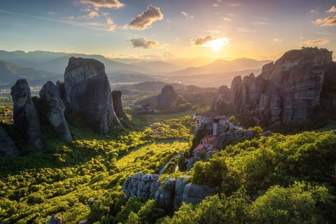 Sunset over monastery of Rousanou and Monastery of St. Nicholas Anapavsa in famous greek tourist destination Meteora in Greece on sunset with sun rays and lens flare
