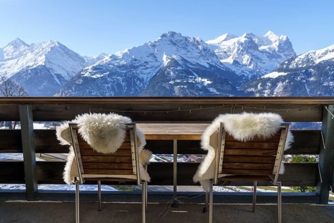 Chairs with fur on balcony in front of mountain panorama