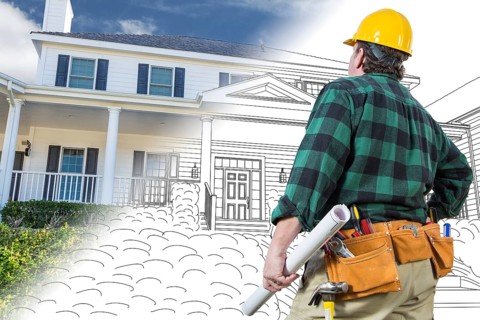 Male contractor with hard hat and tool belt looking at custom house drawing photo combination on white