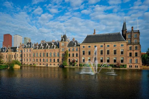 View of the Binnenhof House of Parliament and the Hofvijver lake with downtown skyscrapers in background