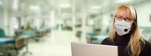 Woman sitting at computer with phone headset within hospital
