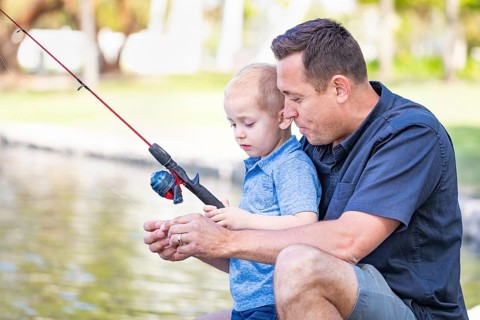 Young caucasian father and son having fun fishing at the lake