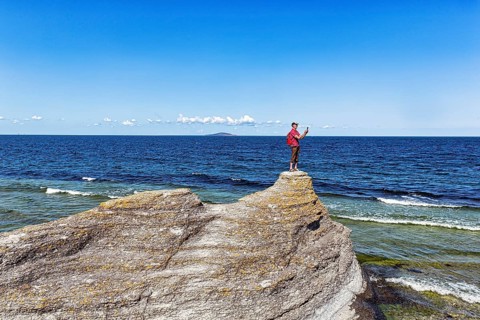 Hiker standing on limestone pillar photographing landscape