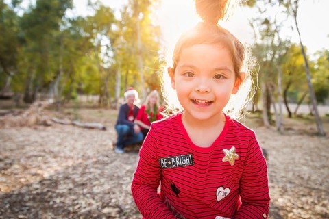 Cute mixed-race baby girl christmas portrait with family behind outdoors