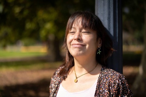 Portrait of a young Latin woman in a park leaning on a lamppost