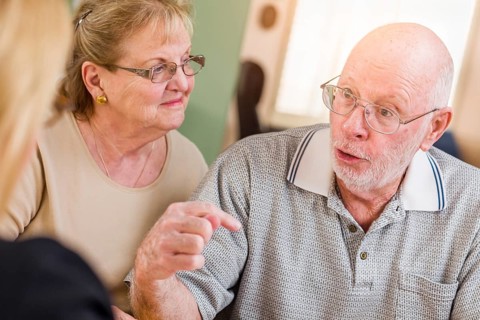 Senior adult couple going over documents in their home with agent at signing