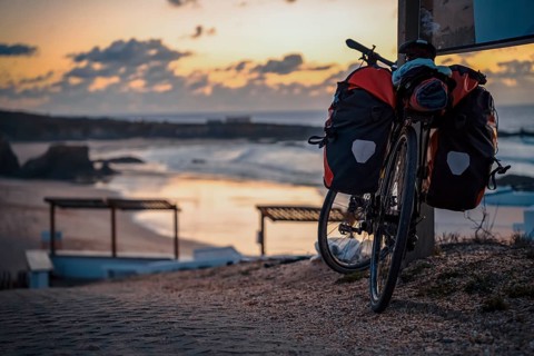 Bicycle with bags by the Almograve beach at sunset