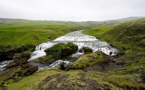 Wide waterfall between green meadows