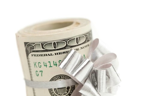 Roll of one hundred dollar bills with silver bow on white