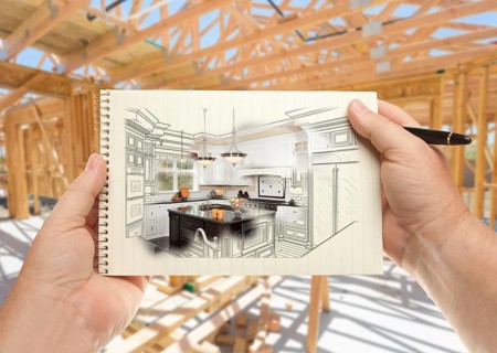 Male hands holding pen and pad of paper with custom kitchen illustration inside construction framing