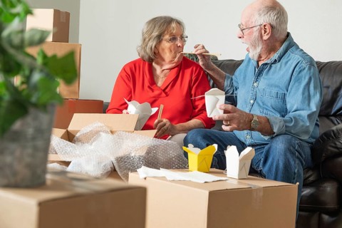 Senior couple enjoying chinese food surrounded by moving boxes