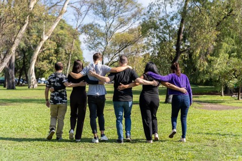 Multi ethnic family group walking arm in arm in a park. Family
