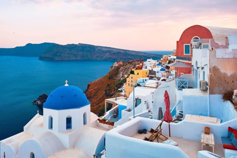 Famous view from viewpoint of Santorini Oia village with blue dome of whitewashed greek orthodox Christian church of traditional greek architecture