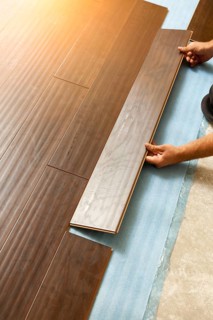 Man installing new laminate wood flooring abstract