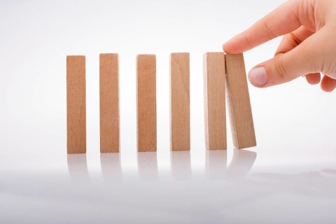 Hand holding wooden domino on a white background