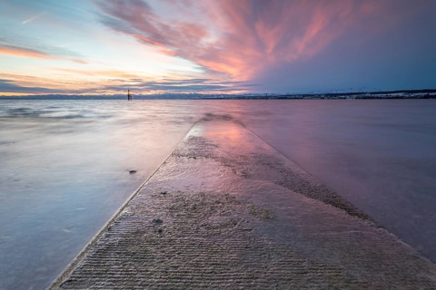 Sunrise on a wintry lake in bad weather
