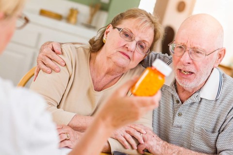 Doctor or nurse explaining prescription medicine to senior adult couple