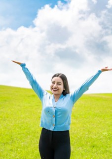 Smiling young woman spreading her arms in the field
