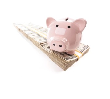 Pink piggy bank on row of hundreds of dollars stacks isolated on a white background